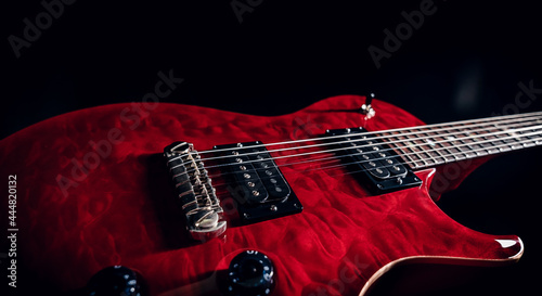 Closeup of a red shiny electric guitar body showing pickups, strings and mechanics