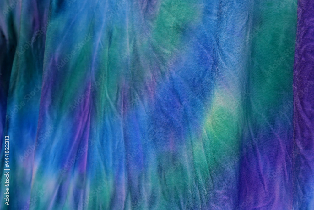 Abstract painted background. Multi-colored pattern in the shibori technique on a thin knitted fabric. Multi-color texture. batik.Textile shibori