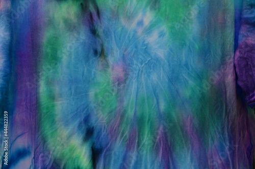 Abstract painted background. Multi-colored pattern in the shibori technique on a thin knitted fabric. Multi-color texture. batik.Textile shibori