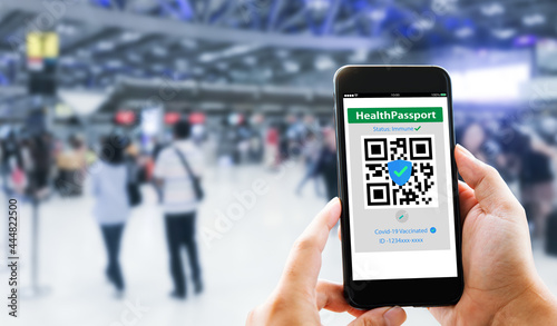 Health Passport Covid-19 Concept.Traveler Hands show Covid-19 Health Passport with blurred airport as background