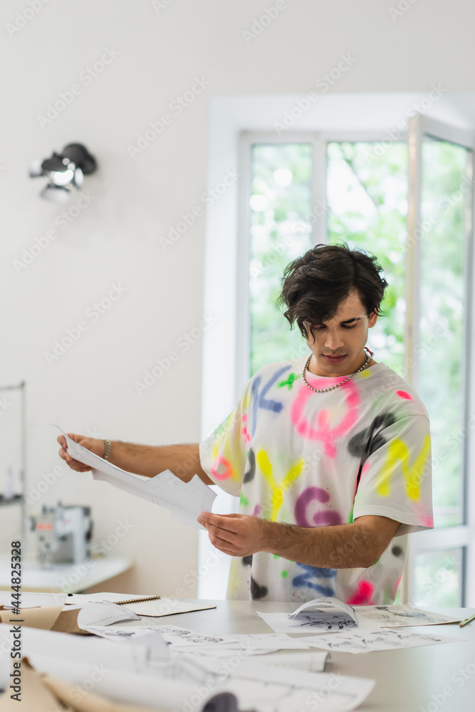 creative fashion designer holding sewing pattern while working in tailor shop