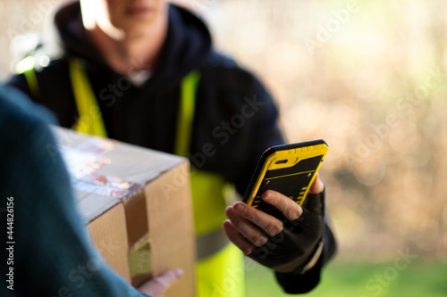 Close up courier with smart phone delivering package photo