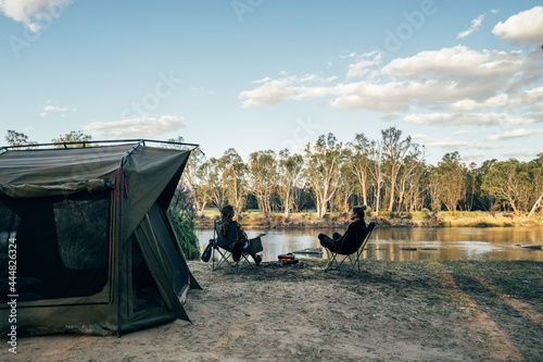 Couple relaxing outside tent at lake in remote Australian bush
