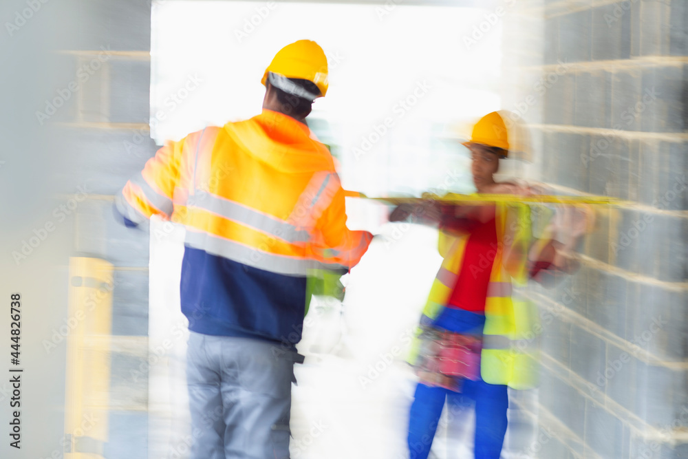 Construction workers with tape measure at construction site