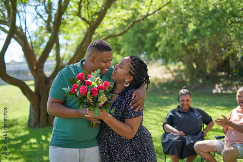 Happy couple with rose bouquet in summer park photo