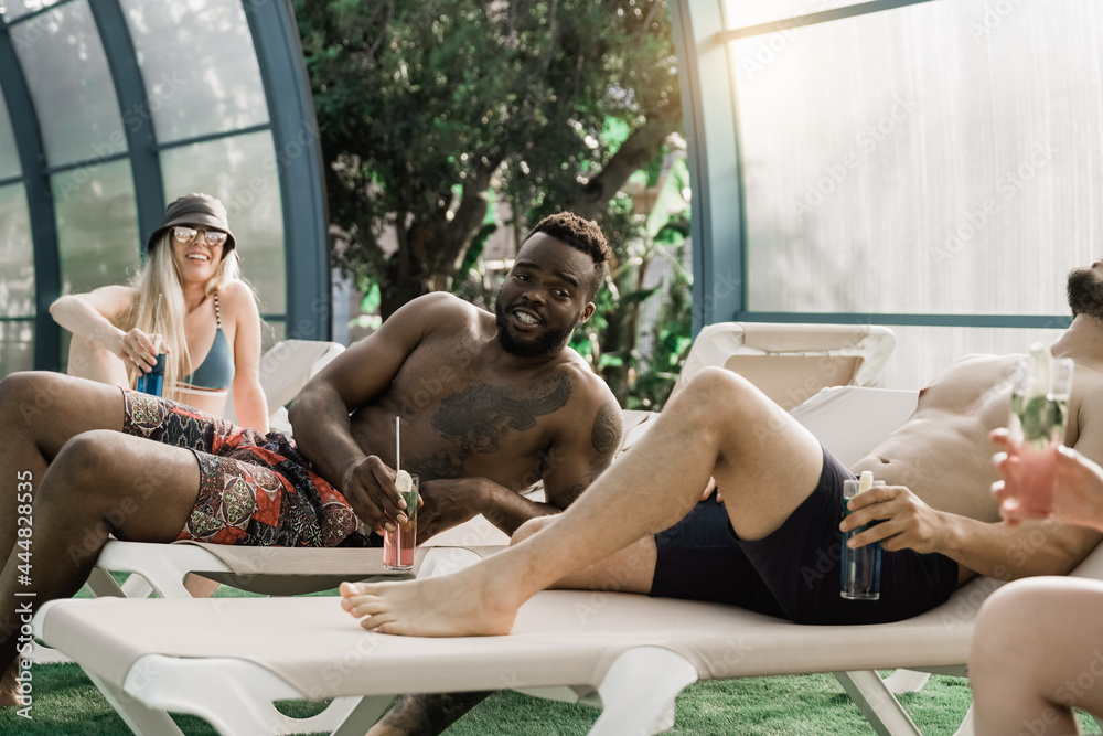 Multiracial people inside indoor swimming pool party having fun during summer vacation at the beach - Focus on african american man face