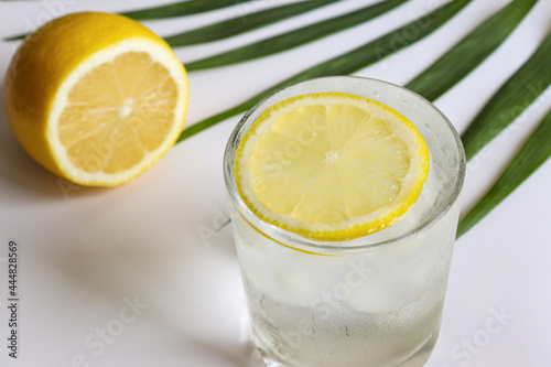 A glass of water with ice cubes and lemon on the table close-up. Summer refreshments and detox concept