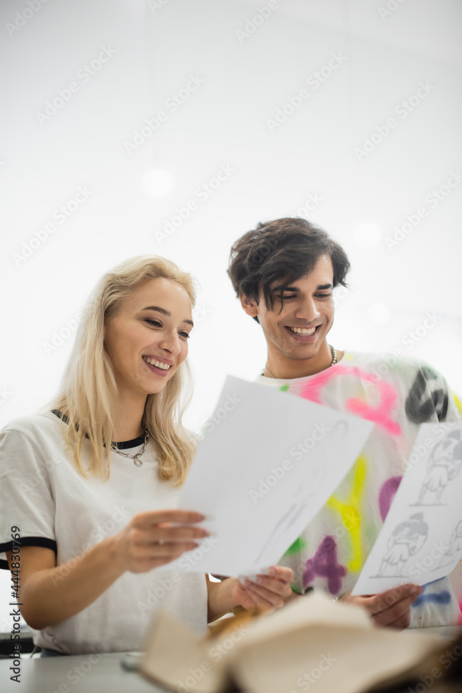 joyful designer looking at drawings in atelier on blurred foreground joyful designer looking at drawings in atelier on blurred foreground