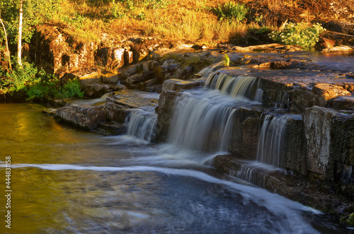 Waterfall with fast moving waters and long exposure. Yellow autumn colors 