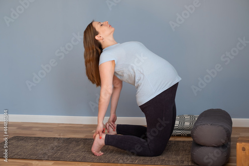 Full length healthy pregnant woman doing yoga exercising stretching at home photo