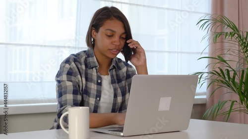 A young woman using a laptop, communicates on the Internet with a client at home. Cozy office workplace, remote work, e-learning concept