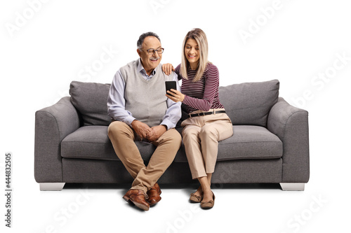 Elderly man and a young woman sitting on a sofa and looking at a mobile phone © Ljupco Smokovski