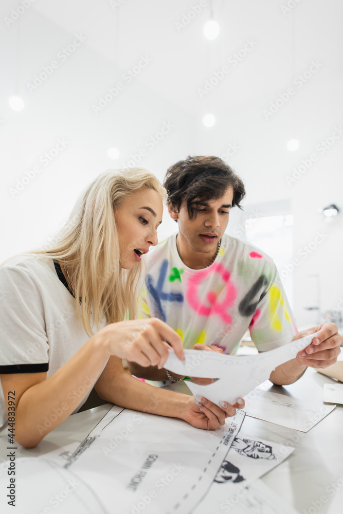 couple of designers looking at sewing pattern while talking in atelier couple of designers looking at sewing pattern while talking in atelier