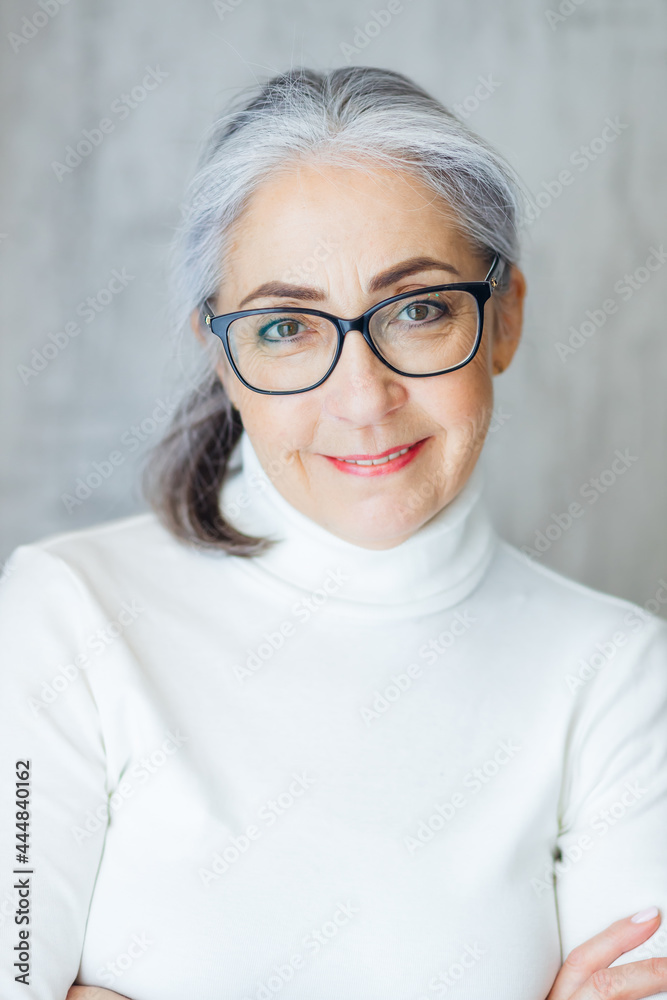 Close-up portrait of smiling mature gray-haired woman with optimism about healthy elderly life, happy elderly grandmother of 60s. Close-up portrait of smiling mature gray-haired woman with optimism about healthy elderly life, happy elderly grandmother of 60s.