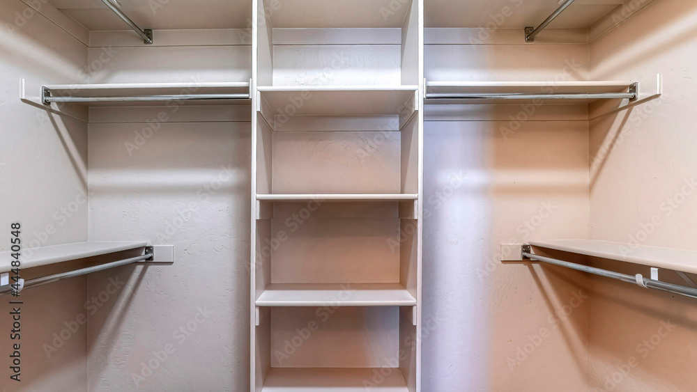 Pano Walk in closet with empty storage shelves for clothes built against white wall Pano Walk in closet with empty storage shelves for clothes built against white wall