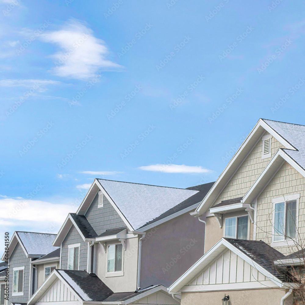 Square Facade of two storey homes on a suburban landscape with blue sky background Square Facade of two storey homes on a suburban landscape with blue sky background