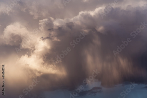 Epic Dramatic storm dark grey white cumulus clouds with rain in sunlight abstract background texture, thunderstorm