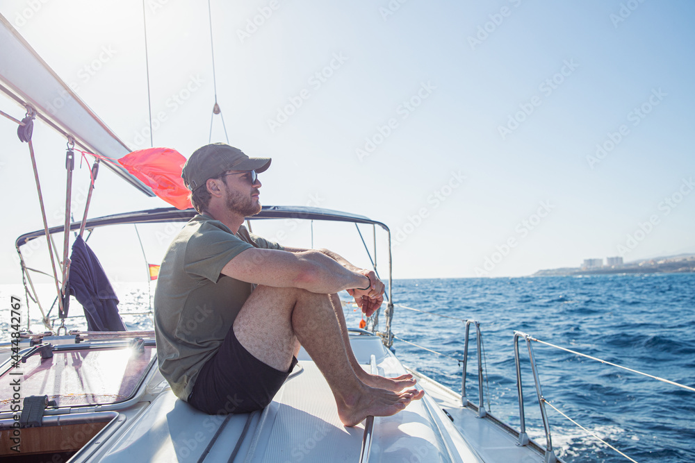A man in a boat sitting, looking at the ocean, he is thinking. Concept of freedom and carefree A man in a boat sitting, looking at the ocean, he is thinking. Concept of freedom and carefree