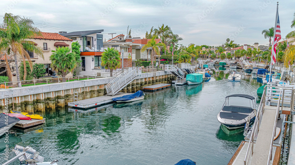 Fototapeta premium Pano Homes lining the canal with boats in charming Long Beach California neighborhood