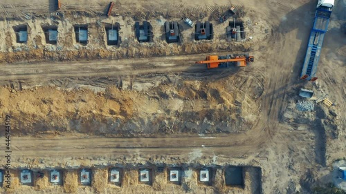 Aerial top-down view of the prepared plot of land (developable site) with concrete-poured foundation supports and construction equipment