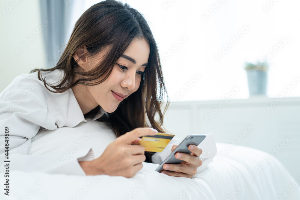 Asian attractive woman enjoy shopping online on bed at home in morning Asian attractive woman enjoy shopping online on bed at home in morning