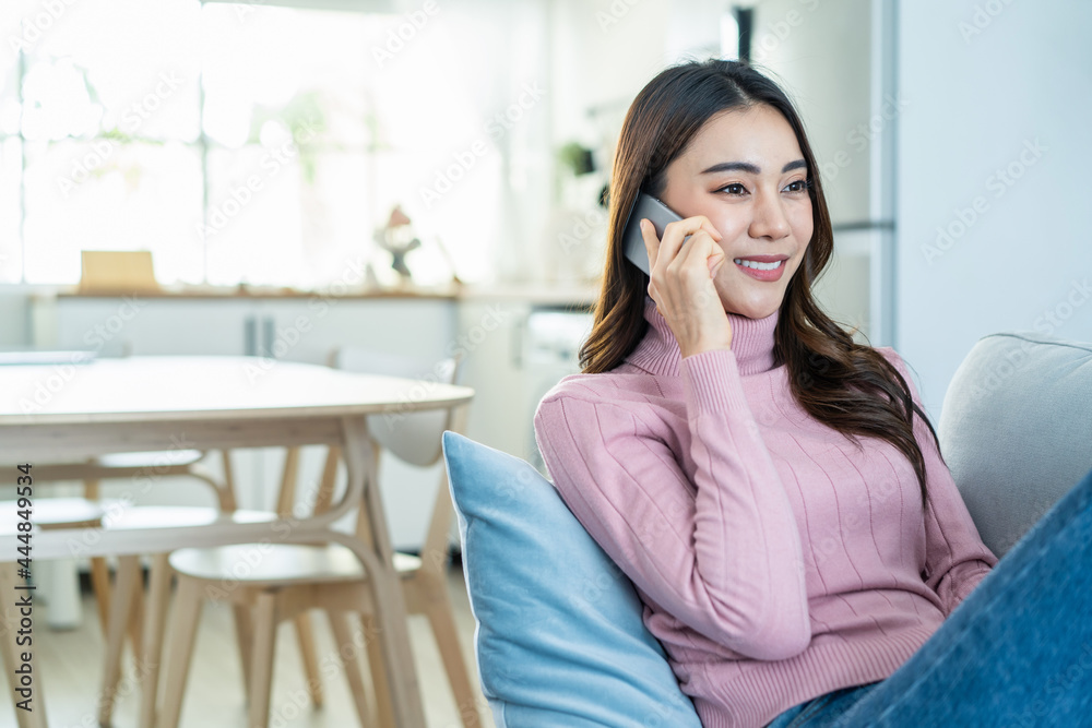 Asian beautiful woman sit on sofa and talk on mobile phone in house. Asian beautiful woman sit on sofa and talk on mobile phone in house.