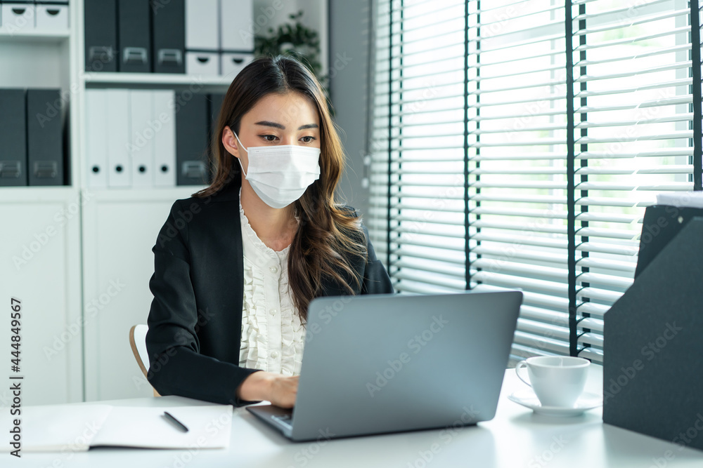 Asian businesswoman in formal suit wear facemask and work at workplace Asian businesswoman in formal suit wear facemask and work at workplace