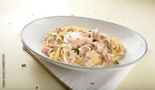 carbonara pasta with chicken ham and half boiled egg in creamy cheese white sauce in white background western halal menu