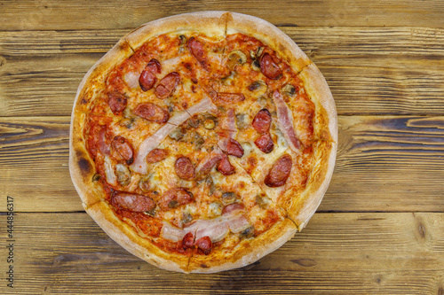 Delicious fresh pizza with sausage, mushrooms and cheese on a wooden table. Top view