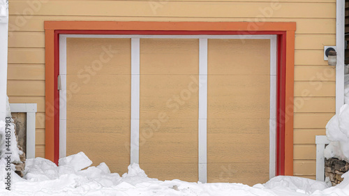 Pano Exterior of an attached single car garage of home with snowy driveway in winter photo