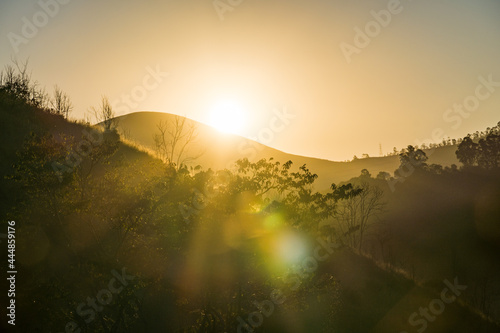 Sunset in the mountains and hills in Itaipava, Petrópolis. Mountain region of Rio de Janeiro, Brazil. Back light in the foreground plants. Selective focus. photo