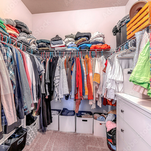 Square Clothes inside a walk in closet of home with carpet on floor and white wall