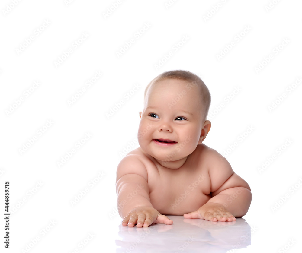 Happy laughing infant child baby girl kid in diaper is lying on her tummy holding arm outstretched, slapping on floor isolated on a white background Happy laughing infant child baby girl kid in diaper is lying on her tummy holding arm outstretched, slapping on floor isolated on a white background