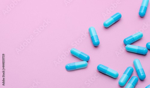 Blue antibiotic capsule pills spread on pink background. Antibiotic drug resistance. Pharmaceutical industry. Healthcare and medicine concept. Health budget concept. Capsule manufacturing industry.