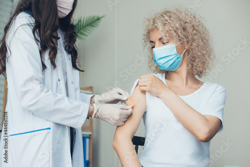 Woman getting vaccination. Happy girl protected by vaccine. Equipped nurse working.