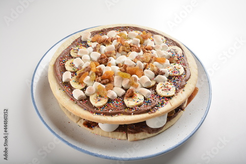 baked chocolate banana pizza with marshmallow and dry grape fruit dessert for kids in white background western halal menu