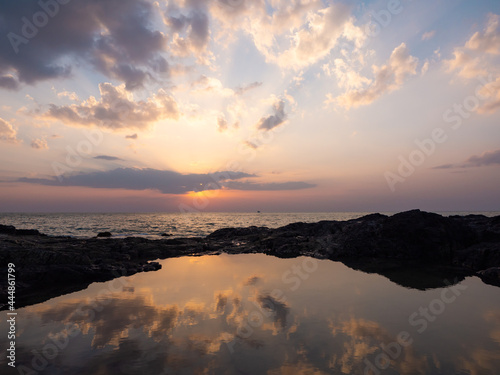 sunset at the horizon. dramatic clouds sky at sea. heavenly twilight sky. sunrays sunbeams shine through dramatic clouds above the ocean. reflection of golden light shines on the water surface.