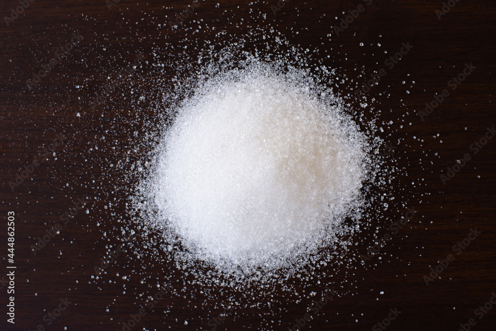 Pile of white sand sugar isolated on dark background. Overhead view. Flat lay. 