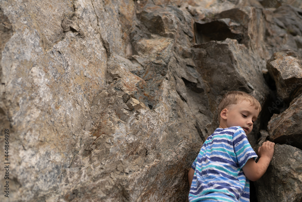 The child climbs up the rock