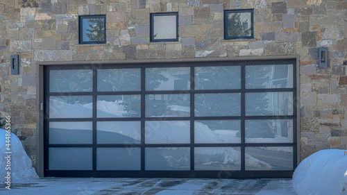 Canvas Print Pano Home with stone wall and glass garage door viewed during winter in Park Cit