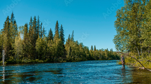 Taiga river nature of the Russian North. Flyfisherman using flyfishing rod in a river.