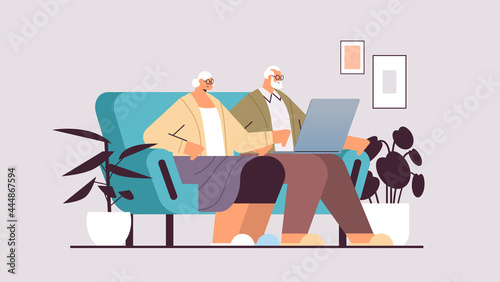 senior couple using laptop grandparents relaxing on sofa at home social media network online communication concept
