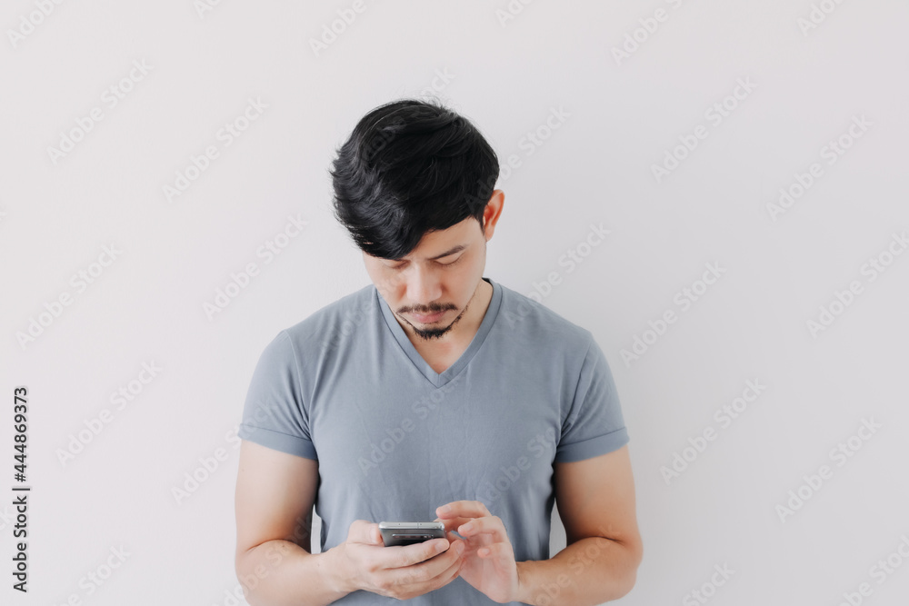 Serious Asian man in blue t-shirt use smartphone isolated on white background. Serious Asian man in blue t-shirt use smartphone isolated on white background.