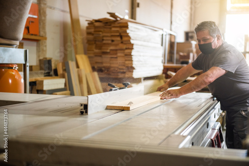 worker cutting some wooden boards in a workshop of carpentry to be processed. Ecological wood