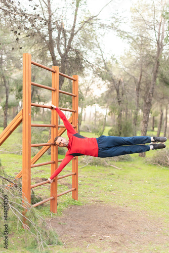 Young man doing exercises on vertical bar in park