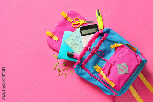 School backpack with stationery on color background