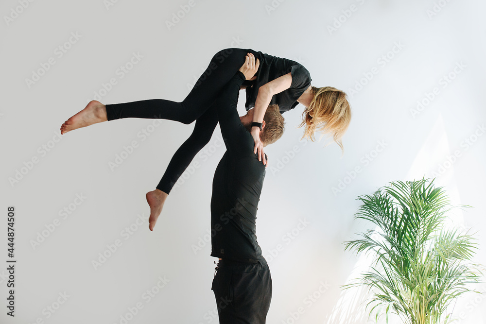 Couple doing gymnastic form, he is holding her on strtaight arms by the ...
