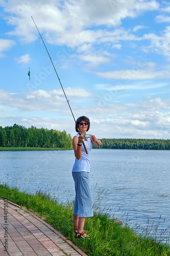 woman fishing on a spinning rod in the lake on summer day, outdoor activities