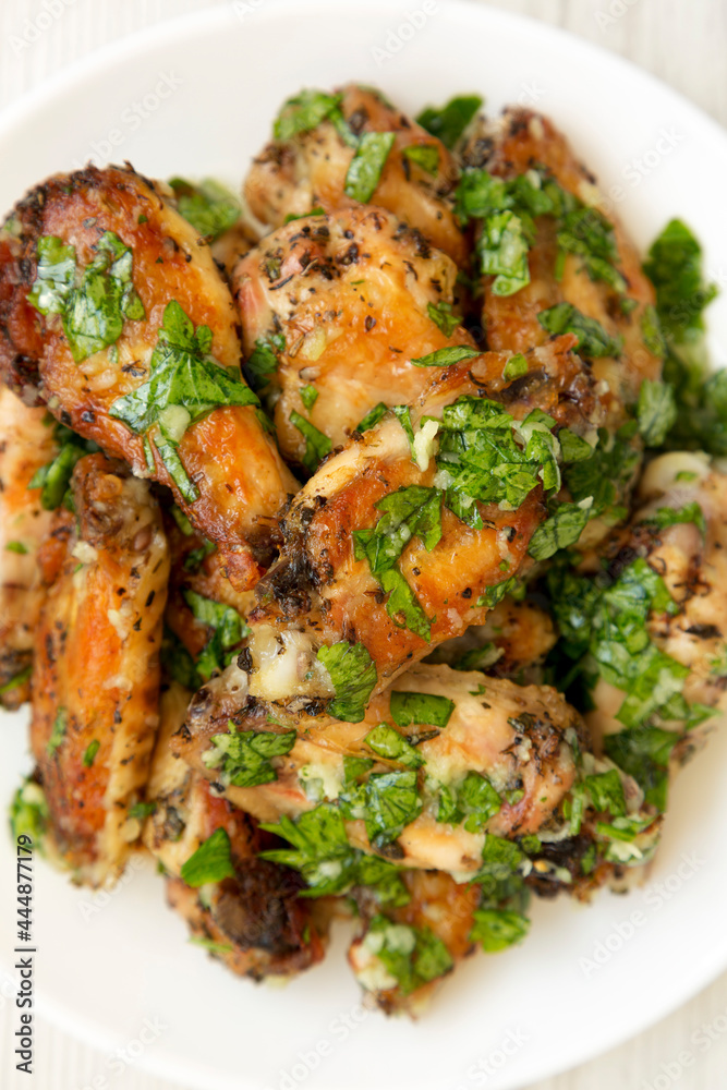 Homemade baked Garlic Parmesan Chicken Wings on a white plate on a white wooden background, top view. Flat lay, overhead, from above. Homemade baked Garlic Parmesan Chicken Wings on a white plate on a white wooden background, top view. Flat lay, overhead, from above.