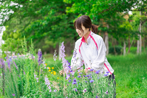 庭で花の世話をする若い女性